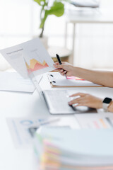 Financial Analysis: A focused individual meticulously reviews financial charts and data on a laptop, analyzing trends with a pen in hand, suggesting analytical precision and business insight.