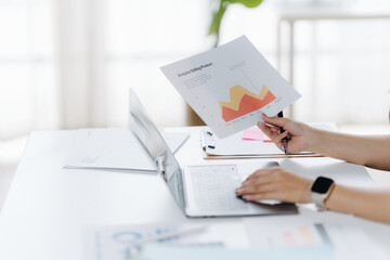 Data Analysis and Digital Workspace: A professional carefully examines financial data while working on a laptop, a symbol of modern work culture and financial planning.