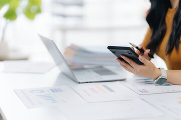 Financial Analysis and Calculation: A focused individual intently reviews financial documents, expertly utilizing a calculator and laptop, meticulously analyzing data to derive valuable insights.