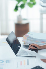 Fototapeta premium Efficiency in Focus: A person is immersed in focused work, their hand moving with purpose as they navigate a laptop's interface, with papers neatly organized beside them.