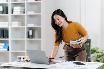 Focused Businesswoman at Work: A dedicated businesswoman, absorbed in her work, meticulously examines documents and operates a laptop.