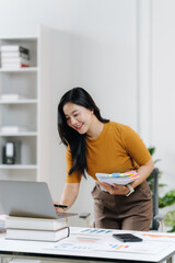Busy Woman in a modern Office: A focused professional, bathed in natural light, interacts with a laptop at a modern workspace, with files and stationary.