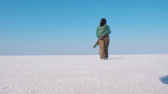 Indian girl walking at White Rann of Kutch in Gujarat, India. Tourist exploring white desert, tourism and holidays concept. Rann Utsav festival in winter season. Landscape of white desert of Kutch.

