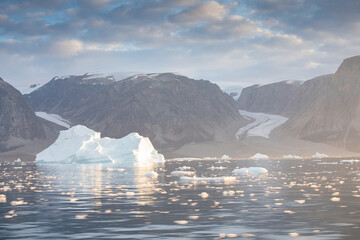 A huge floating iceberg off the coast of Greenland that threatens maritime transport. Ecology, melting ice, climate change, global warming. You can see land in the background. © Michal