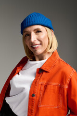 Stylish blonde woman in trendy outfit poses in studio with confidence and charm