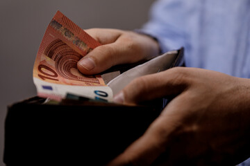 Close-up of a person's hands holding and counting Euro banknotes from a wallet. Financial concept...