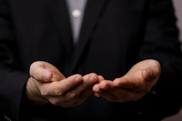 Fototapeta premium Close-up shot of a man in a business suit extending open hands. Concepts of giving, receiving, and offering, perfect for business or assistance