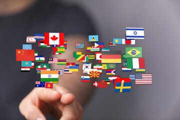 Person's finger touching international flags, symbolizing global connectivity, world countries, and international relations. Focus on cultural d