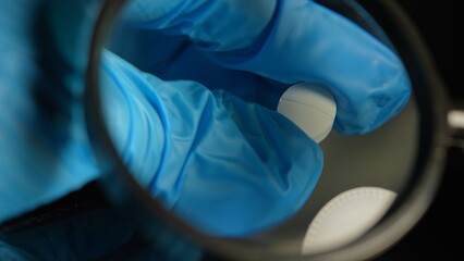 Police investigator in blue gloves studying seized illegal drugs packed in vacuum bag. Forensic science criminalistics. Drugs in shape of pills seized by police. Crime scene and evidence.