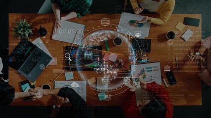 Aerial view of a diverse team engaged in a collaborative meeting with digital graphics showcasing data and strategy concepts, emphasizing teamwork and innovation. Raster - Powered by Adobe
