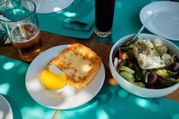 Griechischer Bauernsalat mit Feta und Saganaki mit Zitrone am Tisch © Michael