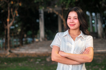 Young woman smiling in a casual white shirt standing outdoors in park setting