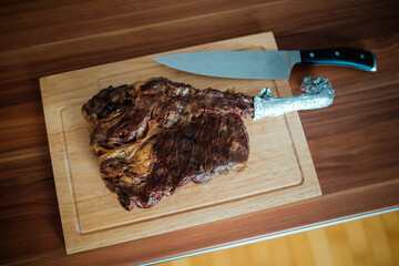 Tomahawk Steak mit Messer auf Holzbrett