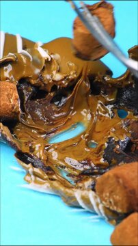 Mini marshmallows in cocoa powder, melted chocolate, close-up, using a fork to take sweets
