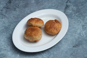 Freshly baked savory bread pastries, beautifully arranged on a crisp white plate. A tempting treat for any culinary project.