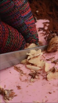 Hazelnuts are cut and crushed with a knife, close-up, to prepare a sweet with a nutty aroma.