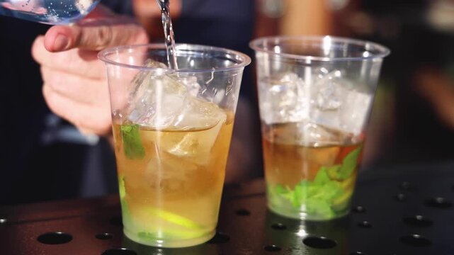 Bartender working, beautiful row line of different coloured liquor alcohol cocktails on a open air party in a bar,  catering banquet on event, barman mixing drinks, selection of beverages in club