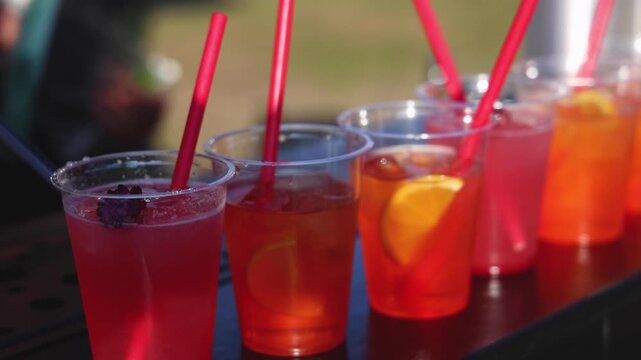 Bartender working, beautiful row line of different coloured liquor alcohol cocktails on a open air party in a bar,  catering banquet on event, barman mixing drinks, selection of beverages in club