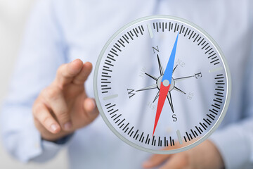 Close-up of hand pointing at compass. Concept of navigation, direction, travel, business strategy, or exploring options and finding the right pa