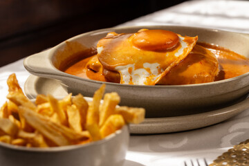 The “Francesinha Especial" traditional from northern Portugal, consists of layers of bread, assorted meats, and melted cheese, served with a hot and slightly spicy sauce.