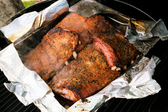 Ger&auml;ucherte und geschmorte St. Louis Cut Ribs (fleischige Bauchrippen vom Schwein), in Edelstahlbr&auml;ter mit aufgerissener Alufolie