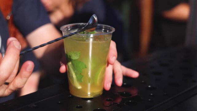 Bartender working, beautiful row line of different coloured liquor alcohol cocktails on a open air party in a bar,  catering banquet on event, barman mixing drinks, selection of beverages in club