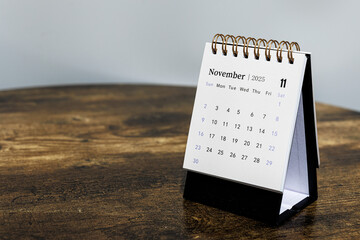 November 2025 monthly calendar page on a wooden desk, minimal design planner representing time management and organization at workplace