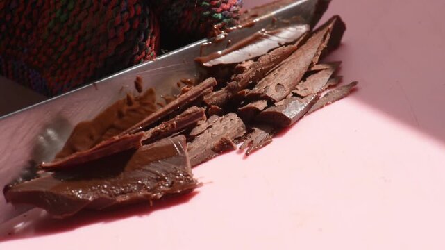 cutting milk chocolate with a knife into small pieces, soft chocolate, cutting smoothly, close-up.