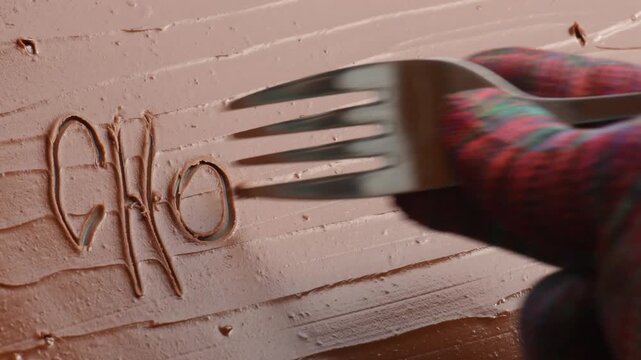 writing the word chocolate on a chocolate cream surface, close-up.