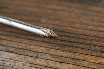 Close-up of a rusty screwdriver on a weathered wooden surface