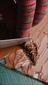 cutting chocolate candies with cream filling, cutting into pieces with a knife, close-up.
