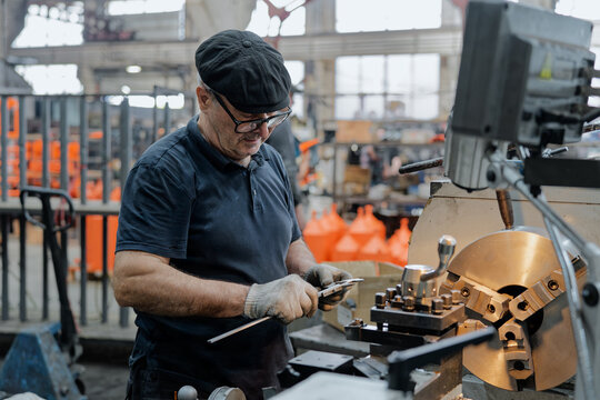 Professional machinist working on industrial lathe, focused on detail and perfection in manufacturing process