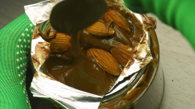 jar of chocolate cream, scooping out cream with a spoon, close-up.