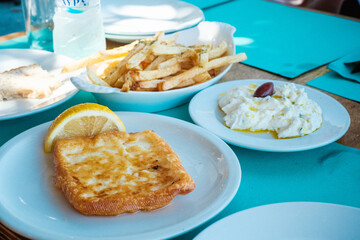 Saganaki (panierter Käse), Tzatziki mit Olive und Pommes frites auf gedecktem Tisch