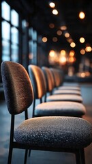 A row of sleek, modern chairs, bathed in warm light, arranged in a venue, offering a sense of anticipation and aesthetic design. 