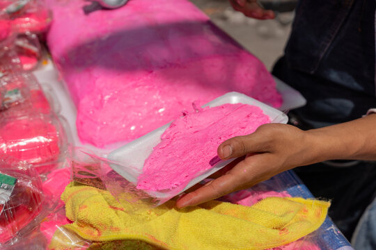 Turr&oacute;n Candy, Close up of a man's hands slicing a block of bright pink artisanal nougat with a long knife. The confection is being sold at a street vendor stand. Turron