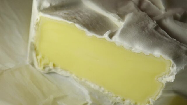 Cutting soft cheese with white mold with a knife, close-up, creamy texture and edible mold close-up.