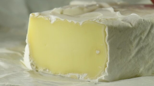 Soft French cheese with white mold, Brie, cut into pieces with a knife, close-up.