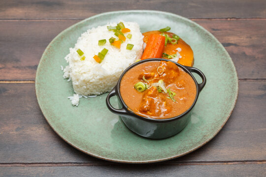 Maf&eacute; &ndash; rago&ucirc;t de viande avec sauce arachide, plat traditionnel ouest-africain pr&eacute;sent&eacute; sur une assiette color&eacute;e, table en bois. Plat s&eacute;n&eacute;galais. Cuisine africaine. 
