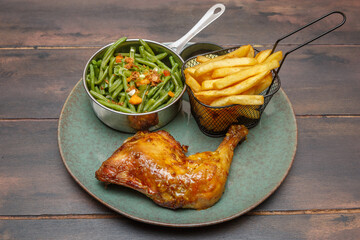Cuisse de poulet avec frites et haricots verts, plat africain traditionnel sur une table en bois. 