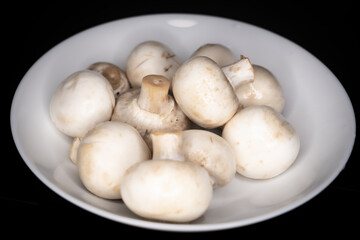 Fresh washed champignon mushrooms on a white plate