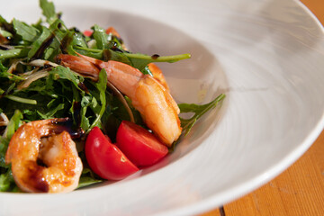 Fresh shrimp salad with arugula and cherry tomatoes served in a bowl