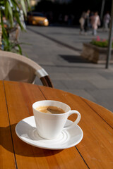 Enjoying a warm cup of coffee at a city café in the sunny afternoon