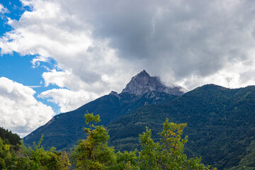 Fototapeta premium Green meadows and cloudy mountains on the road to La Salle-en-Beaumont in the Auvergne-Rhone-Alpes region, France