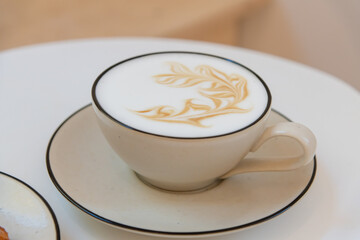 Beautiful latte art displayed on a creamy cup of coffee with cookie