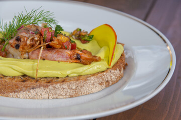 Delicious shrimp toast topped with creamy avocado and fresh herbs