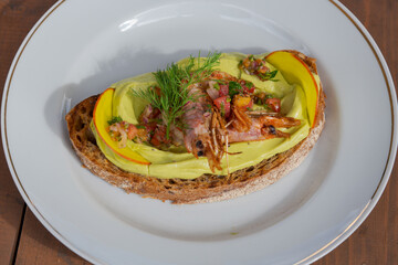 Shrimp avocado toast with fresh veggies on rustic bread