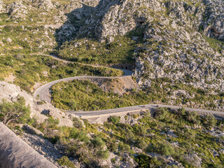 Serpentine road to Sa Calobra, Mallorca, winding road snakes through rugged, rocky mountains with sparse green vegetation, offering a scenic drive, Majorca