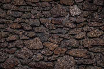 Textured granite boulder masonry with deep, dark joints. Natural stone texture