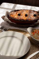 The "Bacalhau com Natas", a traditional Portuguese oven-baked codfish dish made with flaked cod, potatoes and onions, baked until golden and creamy, and often topped with black olives.